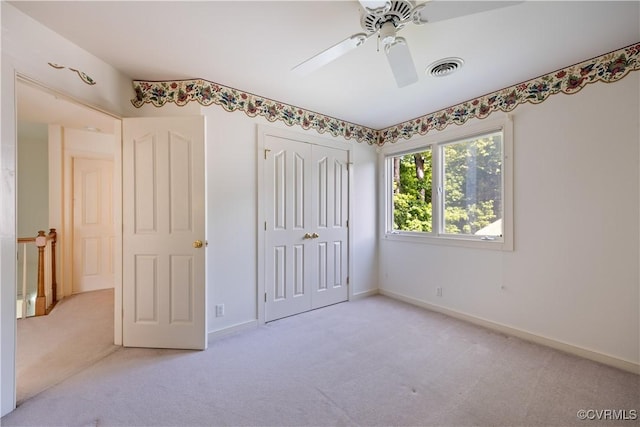 unfurnished bedroom with light carpet, a closet, baseboards, and ceiling fan