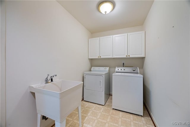 laundry room featuring washer and clothes dryer, cabinet space, light floors, and baseboards