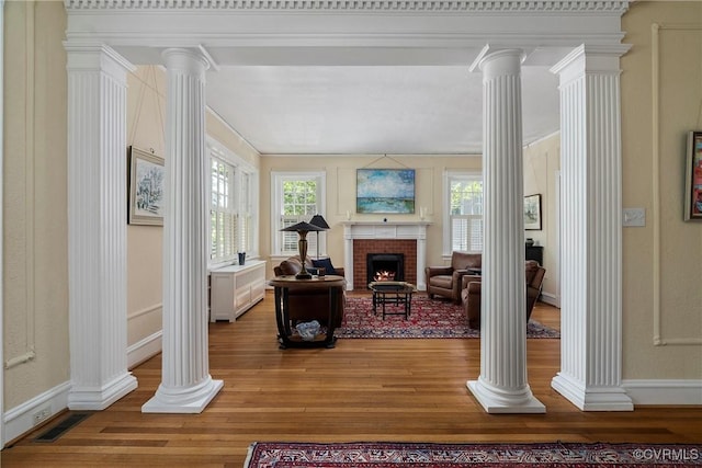 3201 Kensington Ave, Richmond, VA 23221 - living room featuring decorative columns, light wood-style floors, a fireplace, crown molding, and baseboards