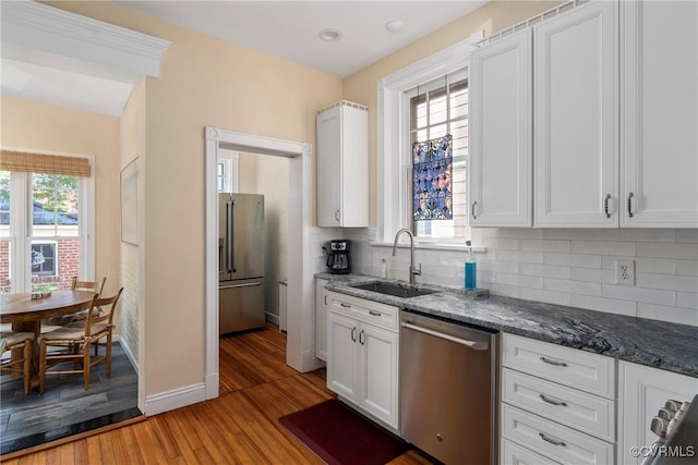 3201 Kensington Ave, Richmond, VA 23221 - kitchen with appliances with stainless steel finishes, a sink, light wood-style floors, tasteful backsplash, and dark stone countertops