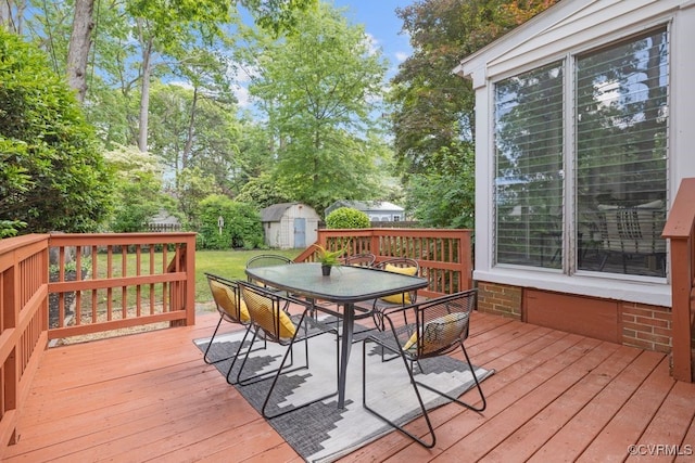 deck featuring outdoor dining space, a storage shed, an outbuilding, and view of scattered trees