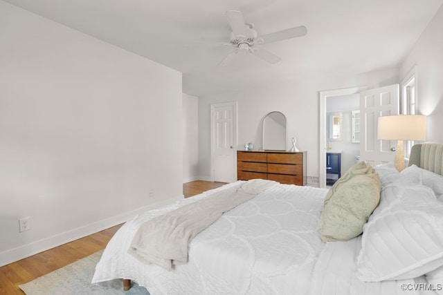 bedroom with baseboards, light wood finished floors, a ceiling fan, and ensuite bath