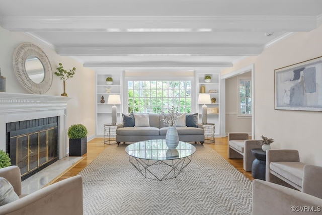 living area with beam ceiling, wood finished floors, a fireplace with flush hearth, crown molding, and built in features