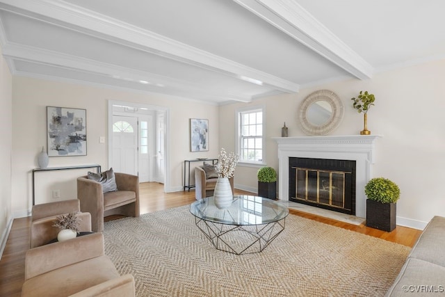 living area featuring a fireplace with flush hearth, wood finished floors, beamed ceiling, baseboards, and crown molding