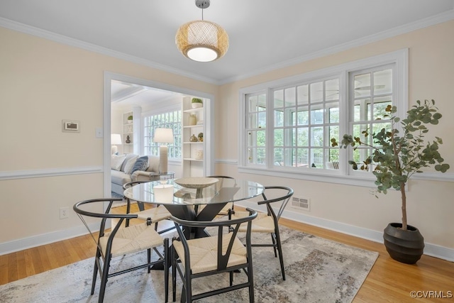 dining area with wood finished floors, ornamental molding, and baseboards