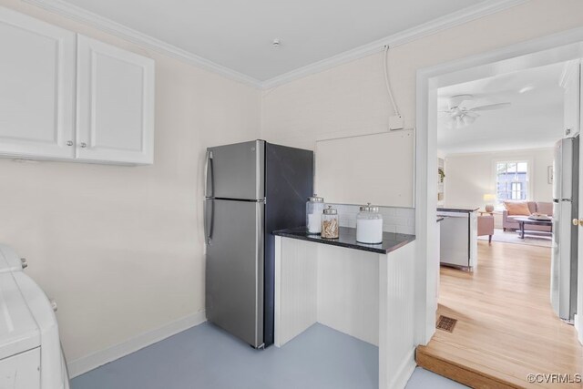kitchen featuring appliances with stainless steel finishes, white cabinetry, dark countertops, ceiling fan, and washer / dryer