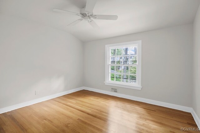 empty room with baseboards, wood finished floors, ceiling fan, and vaulted ceiling