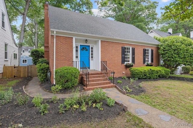 view of front of property featuring brick siding, a chimney, fence, and roof with shingles