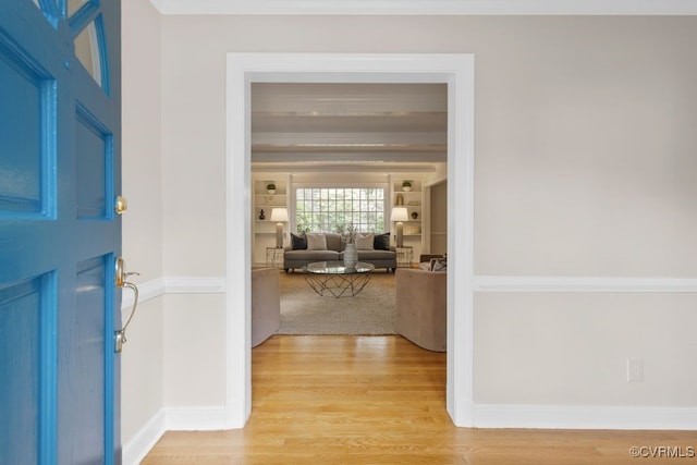 foyer entrance featuring light wood finished floors, ornamental molding, and baseboards
