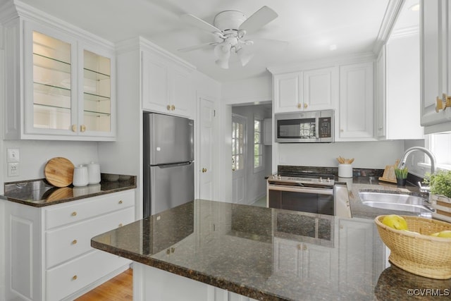kitchen with stainless steel appliances, a sink, white cabinets, and glass insert cabinets