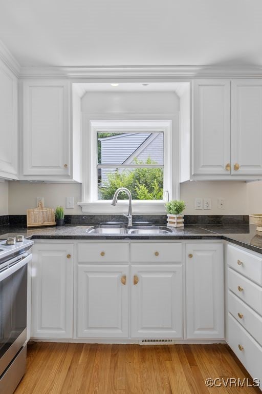 kitchen featuring a sink, stainless steel electric stove, and white cabinetry