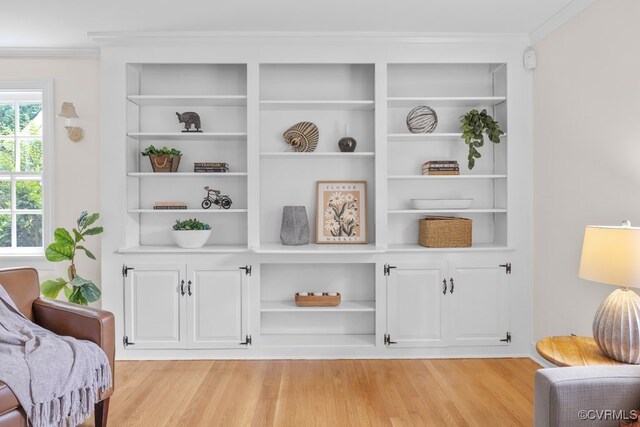 sitting room featuring light wood-style floors, ornamental molding, and built in shelves