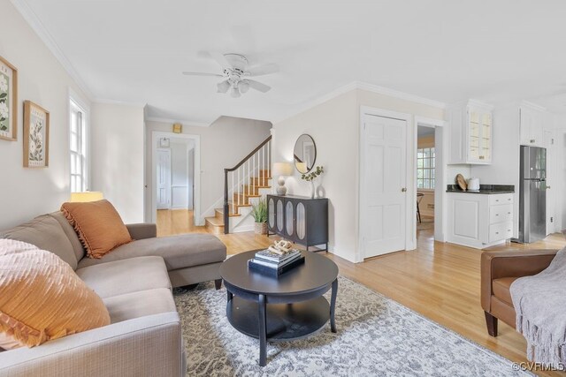 living room with light wood-style floors, stairway, crown molding, and ceiling fan