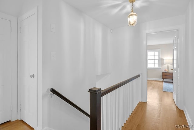 hallway featuring an upstairs landing, light wood finished floors, and baseboards