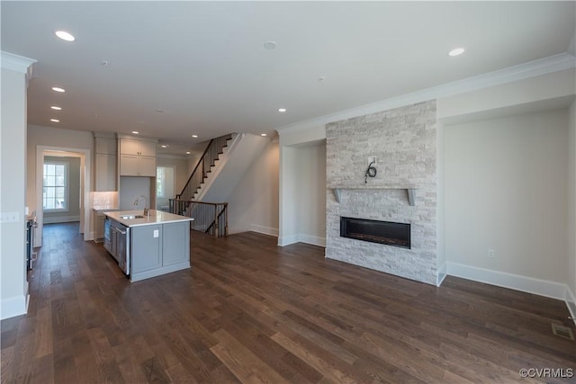 3325 Haydenpark Ln, Henrico, VA 23233 - kitchen featuring open floor plan, ornamental molding, a center island with sink, a stone fireplace, and light countertops