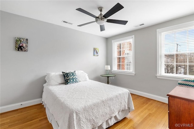 bedroom with light wood finished floors, baseboards, and a ceiling fan