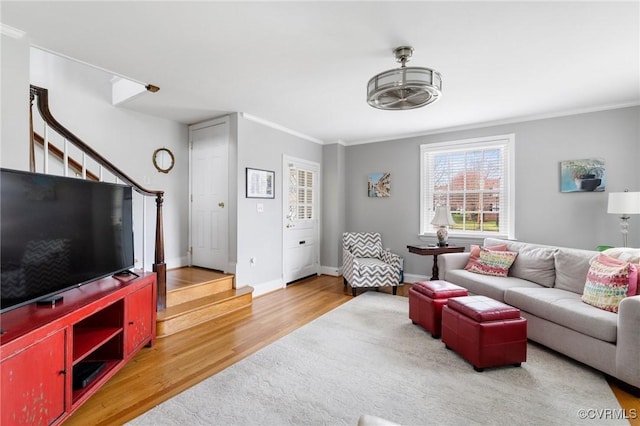 living room with stairs, light wood-style flooring, ornamental molding, and baseboards