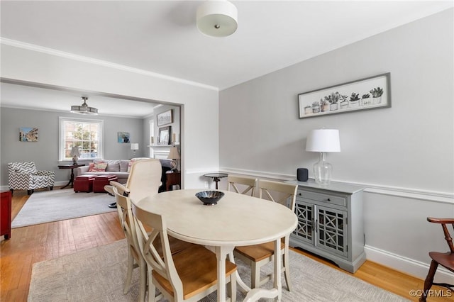 dining area with wood finished floors, ornamental molding, and baseboards