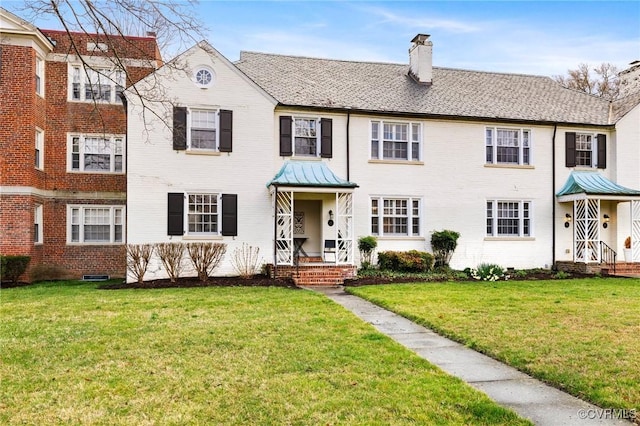 multi unit property featuring a chimney, brick siding, and a front lawn