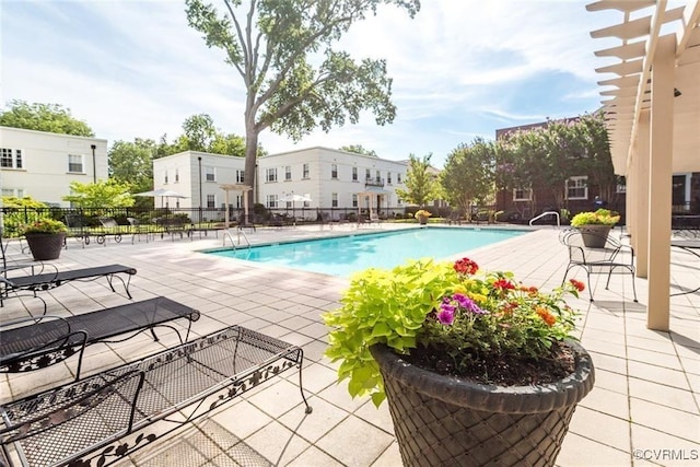 community pool featuring fence, a patio area, and a residential view