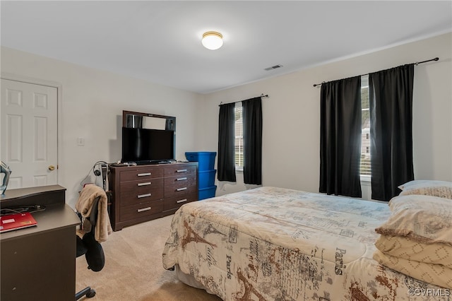 bedroom with light colored carpet and an office area