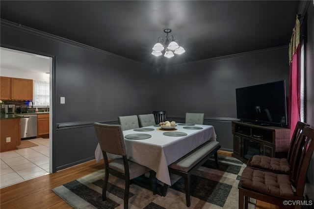 dining space with a chandelier, ornamental molding, and light wood-type flooring