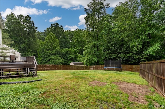 view of yard featuring a trampoline and a wooden deck