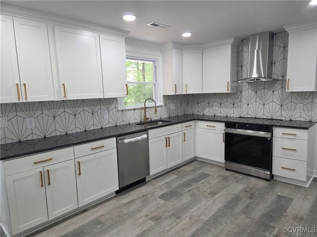 kitchen featuring wall chimney exhaust hood, dishwasher, a sink, dark countertops, and range with electric cooktop