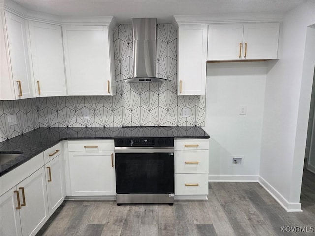 kitchen featuring wall chimney exhaust hood, oven, tasteful backsplash, and white cabinets