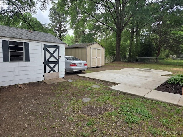 view of yard featuring a storage unit, fence, an outbuilding, and a patio