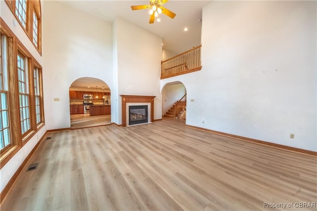 319 Parrotts Cove Rd, Water View, VA 23180 - unfurnished living room with ceiling fan, a glass covered fireplace, arched walkways, a high ceiling, and baseboards