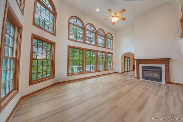 319 Parrotts Cove Rd, Water View, VA 23180 - unfurnished living room featuring a high ceiling, baseboards, a tiled fireplace, wood finished floors, and ceiling fan
