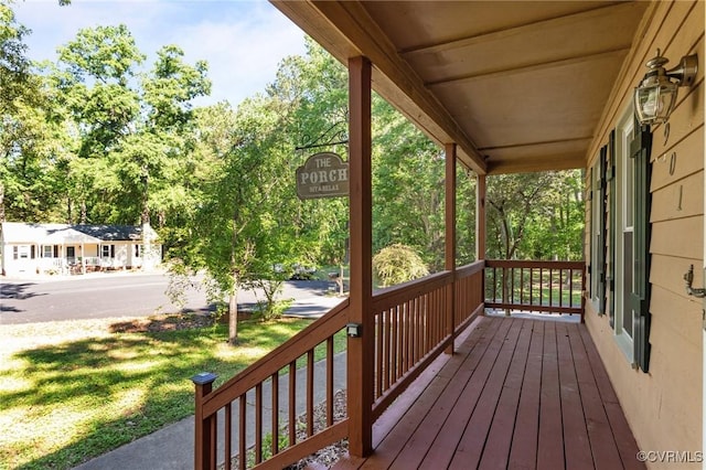 wooden deck featuring covered porch and a lawn