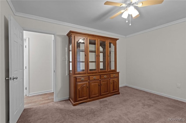 empty room featuring light colored carpet, ceiling fan, crown molding, and baseboards