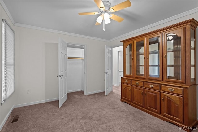 unfurnished bedroom with light carpet, ornamental molding, baseboards, a closet, and a ceiling fan