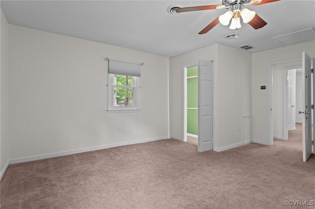 carpeted empty room featuring a ceiling fan, baseboards, and attic access