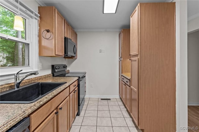 kitchen with black appliances, a sink, light tile patterned floors, baseboards, and crown molding