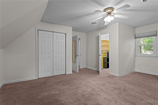 unfurnished bedroom featuring carpet floors, vaulted ceiling, ceiling fan, baseboards, and a closet