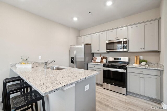 6024 Banyan Ln, Chesterfield, VA 23234 - kitchen with stainless steel appliances, a sink, a peninsula, light wood-type flooring, and a breakfast bar