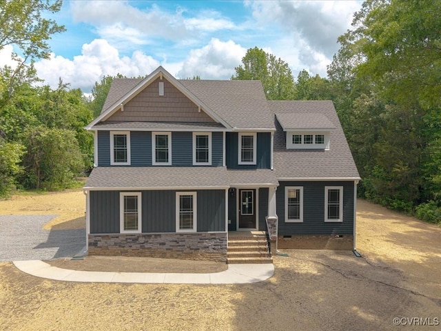 craftsman-style home featuring roof with shingles, a porch, crawl space, board and batten siding, and stone siding