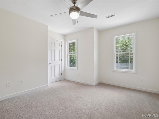 unfurnished room with healthy amount of natural light, light carpet, and baseboards
