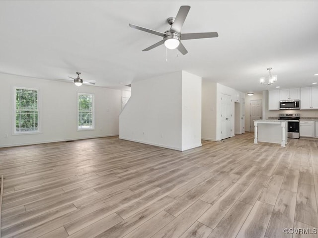 unfurnished living room featuring a chandelier, a ceiling fan, and light wood-style flooring