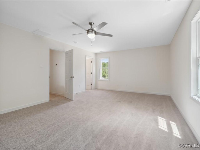 empty room with a ceiling fan, light colored carpet, and baseboards
