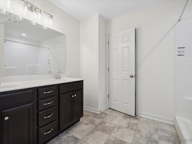 full bathroom with baseboards, double vanity, and a shower