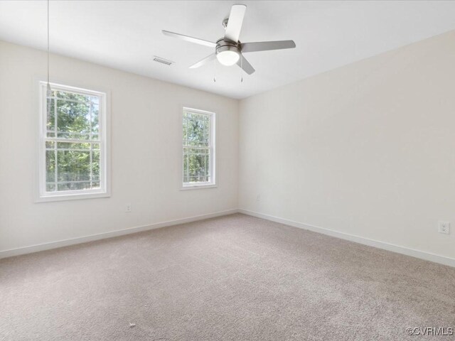empty room with healthy amount of natural light, baseboards, and carpet