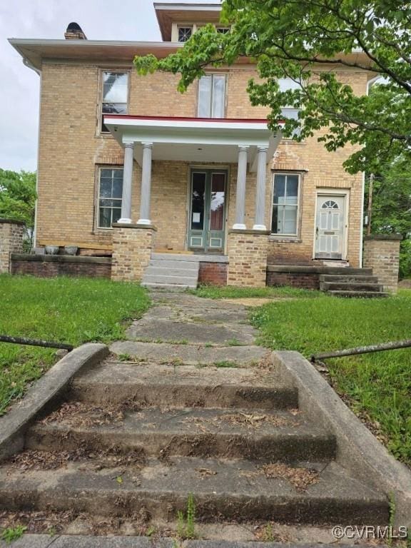 view of exterior entry with brick siding and a porch
