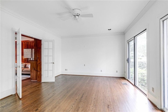 unfurnished room with plenty of natural light, wood finished floors, ornamental molding, a ceiling fan, and baseboards