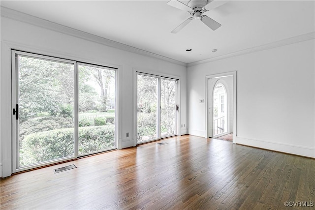 unfurnished living room with wood finished floors, ornamental molding, a ceiling fan, and baseboards