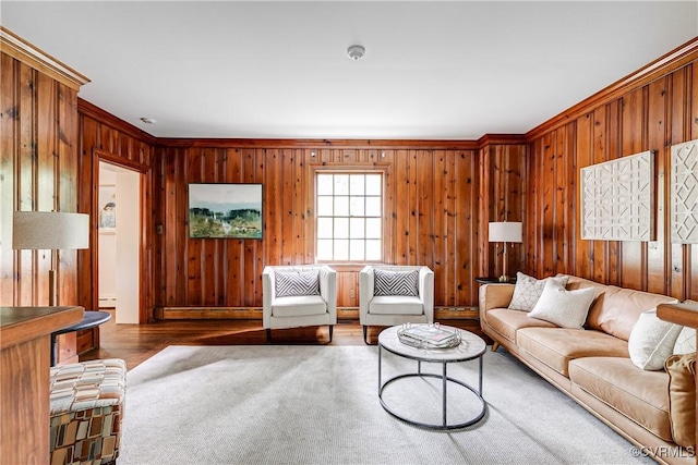 living room with ornamental molding, wooden walls, wood finished floors, and a baseboard heating unit