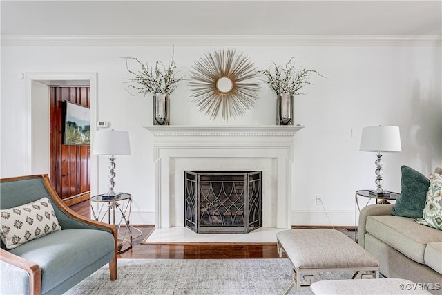 living area with wood finished floors, ornamental molding, baseboards, and a fireplace